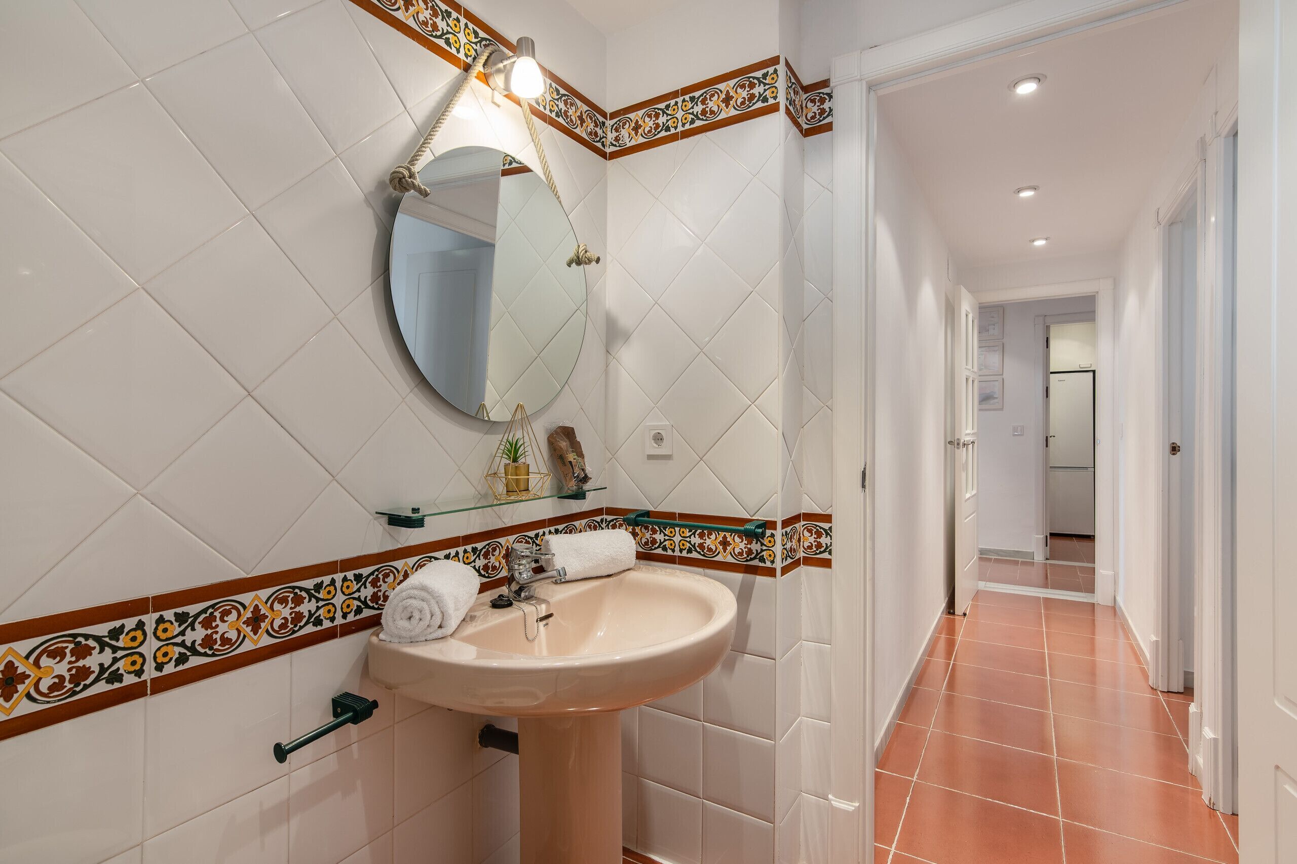 A bathroom with a sink, mirror, and decorative tiles.