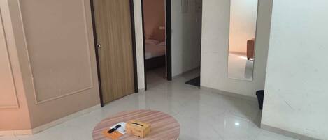 A hallway with a round table, a door, and a mirror on the wall.
