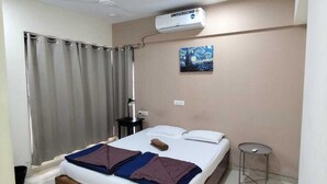 Ein Schlafzimmer mit Bett, Nachttisch, Klimaanlage, Deckenventilator und einem Bild an der Wand.