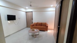 Ein modernes Wohnzimmer mit Sofa, Couchtisch, Wand-Fernseher und Deckenventilator.