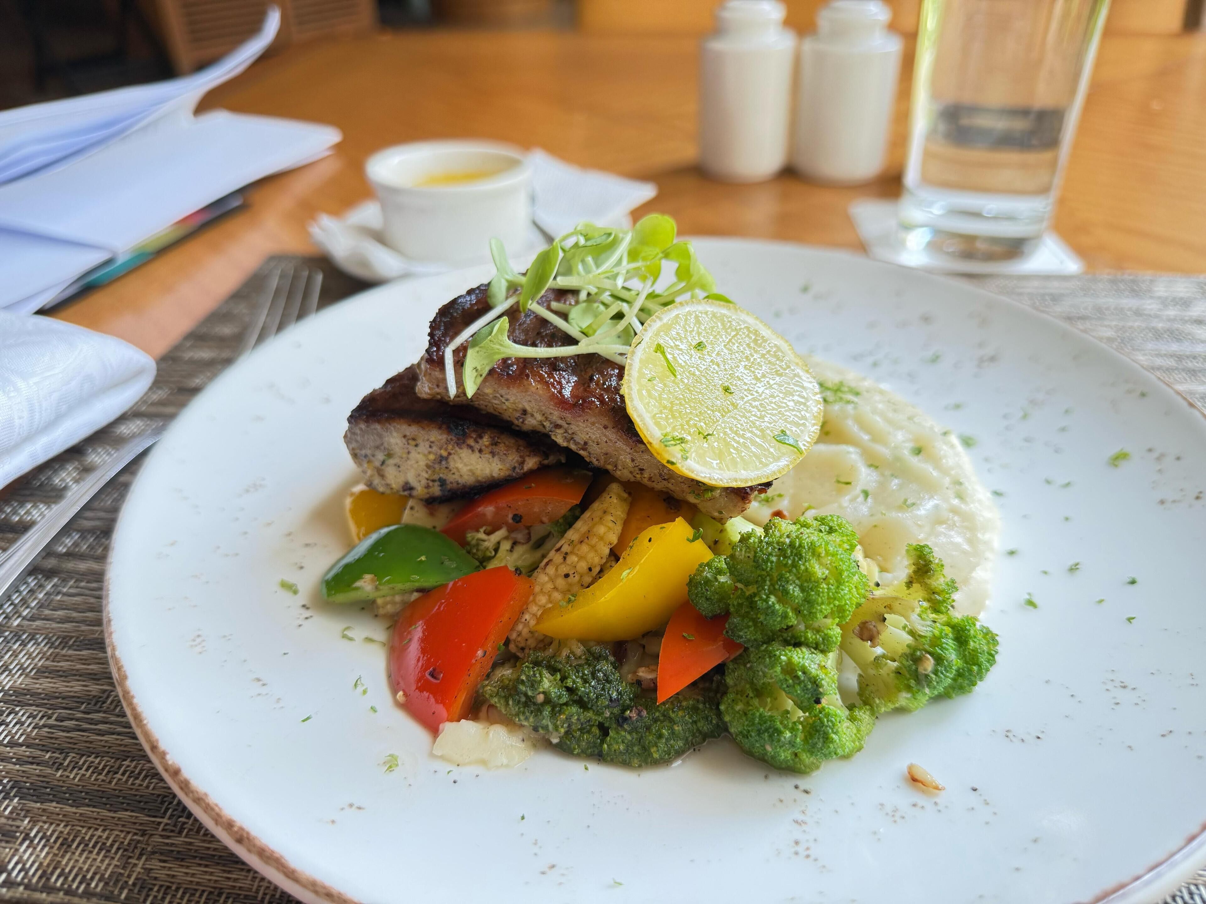 A plate of food with a variety of vegetables and a slice of lemon on top.