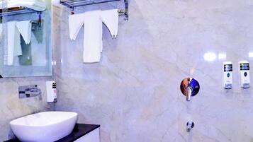 A modern bathroom with a large white sink, a glass shower enclosure, and a marble wall.