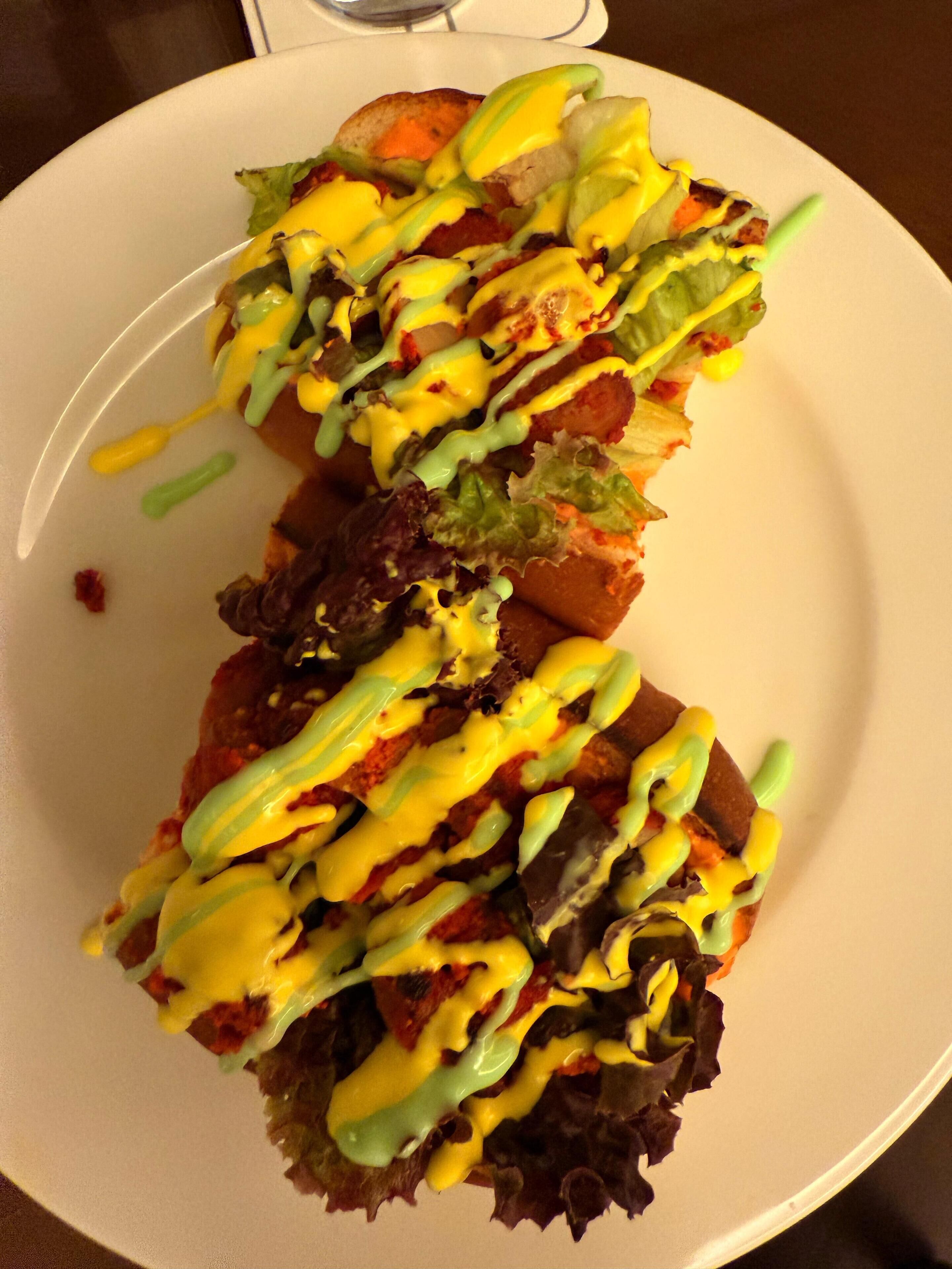 A plate of nachos topped with cheese, lettuce, and a yellow sauce.