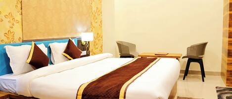 A hotel room with a large bed, two chairs, a small table, and a nightstand.