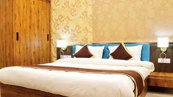 A neatly made bed with a wooden headboard, a nightstand with a lamp, and a wardrobe with a floral wallpaper pattern.
