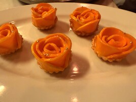 Un plato blanco con seis pequeñas pastas con forma de rosa.