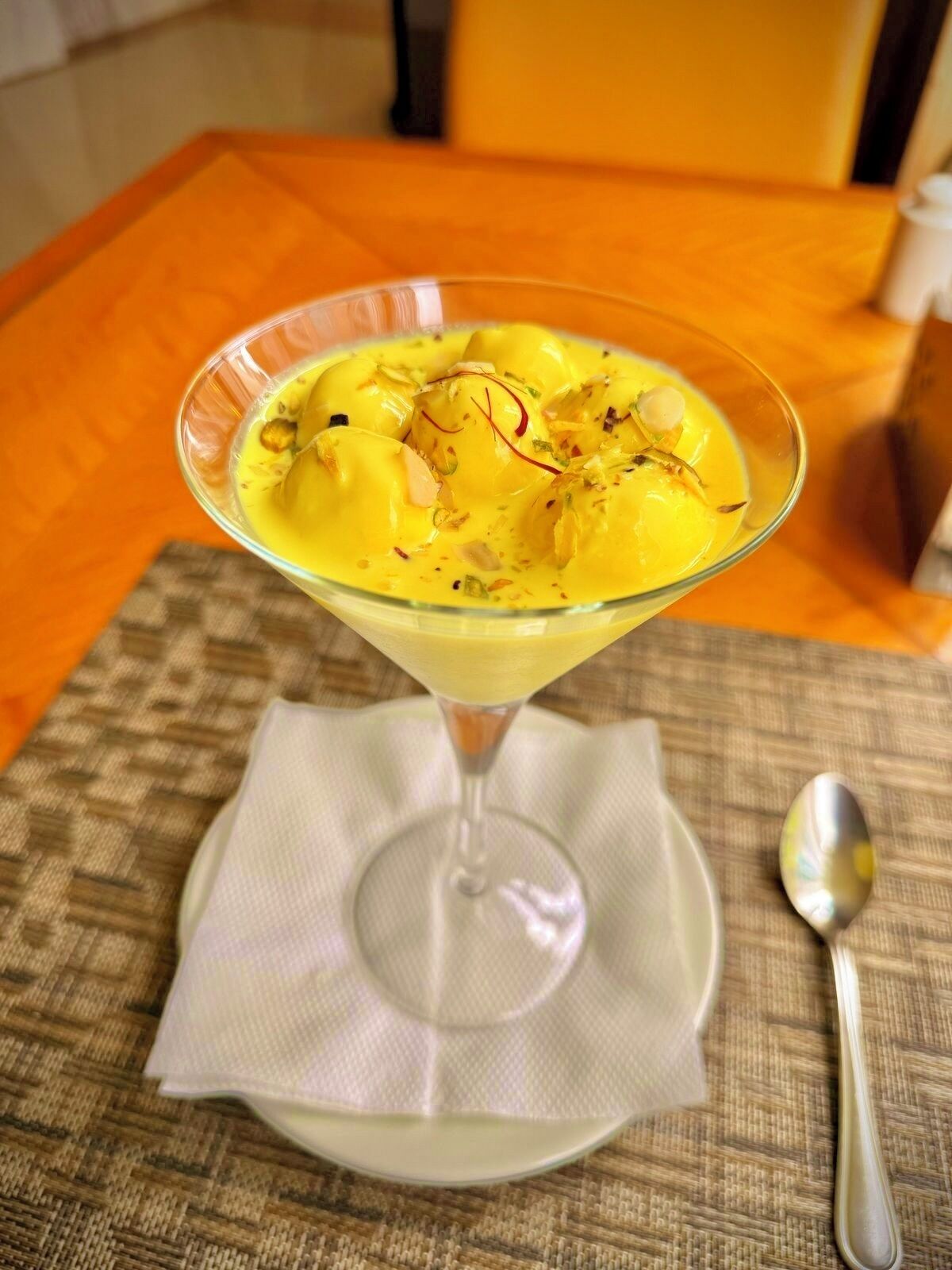 Dessert in een martini-glas op een tafel met een servet en lepel.
