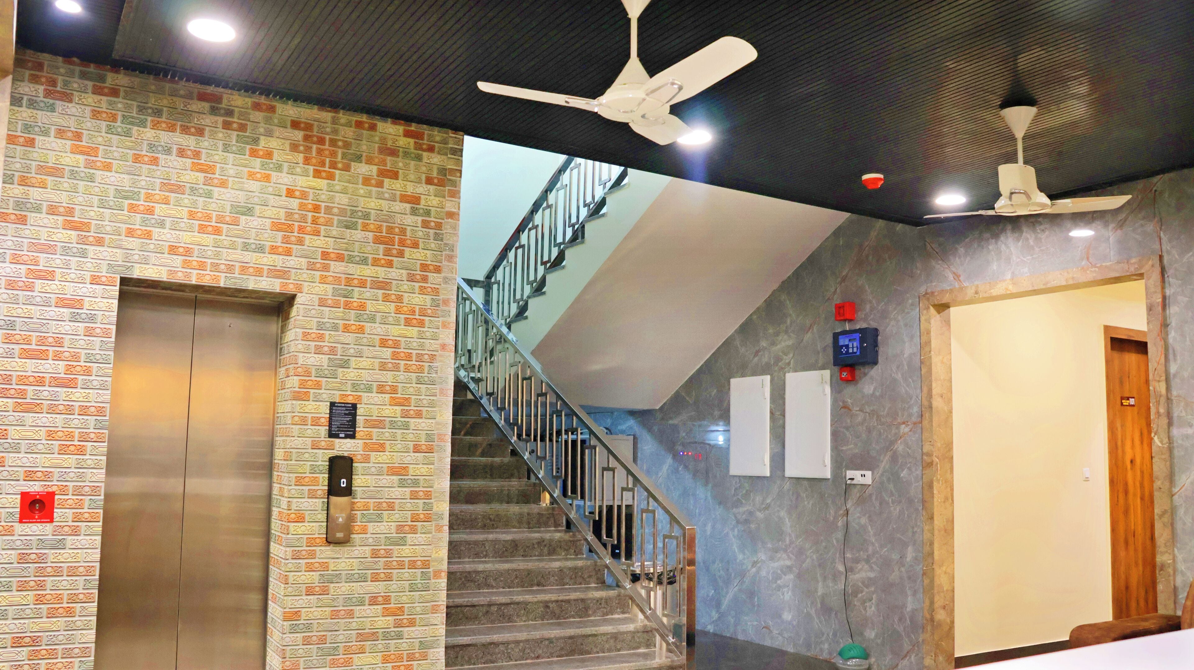 A modern interior with a brick-patterned wall, a staircase, and a ceiling fan.