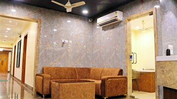 A modern lobby with a marble wall, a sofa, a ceiling fan, and an air conditioning unit.
