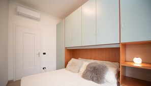 A bedroom with a bed, a wardrobe, and a shelf with a lamp. - La Casa del Lago in Manerba del Garda (Manerba del Garda)