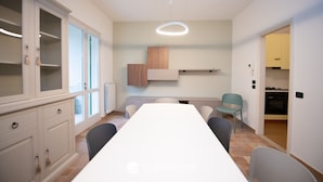 A modern kitchen with white cabinets, a central island, and a dining area with a long table and chairs. - La Casa del Lago in Manerba del Garda (Manerba del Garda)