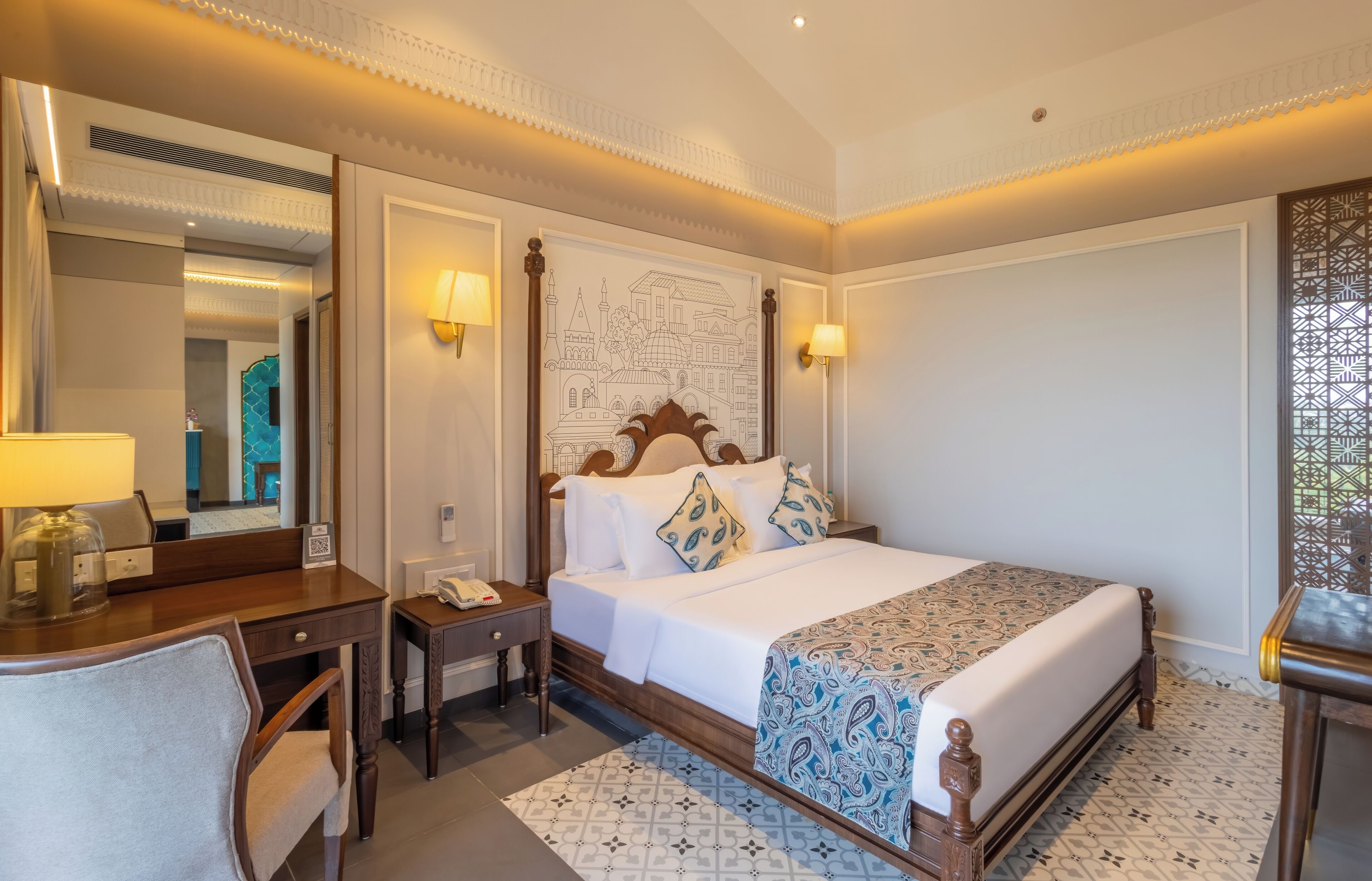 Habitación de hotel con una cama grande, un escritorio, una silla, un espejo y un adorno en la pared.