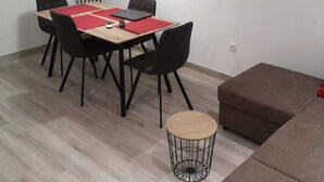 A modern living room with a dining area, featuring a flat-screen TV mounted on the wall, a round coffee table, and a brown sectional sofa. - Apartman Sea Lake Magic 1 (Vinodol)