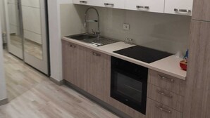 A modern kitchen with white cabinets, a stainless steel sink, and a built-in oven. - Apartman Sea Lake Magic 1 (Vinodol)