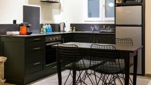 A compact kitchen with a dining area, a built-in oven, a microwave, and a clock on the wall.