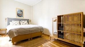 A bedroom with a bed, a wooden wardrobe, and a painting on the wall.