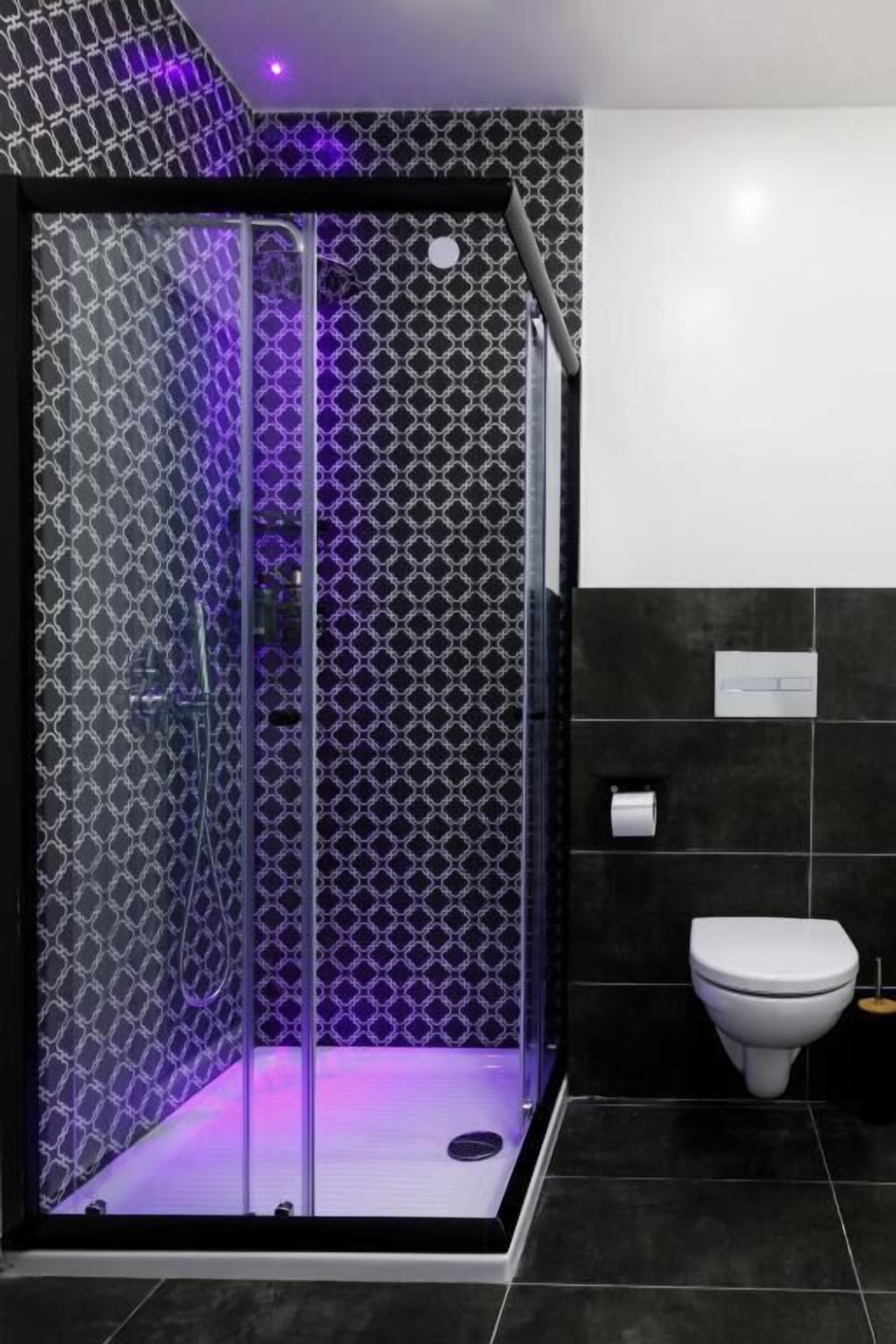 A modern bathroom with a glass-enclosed shower, a toilet, and a patterned wall.