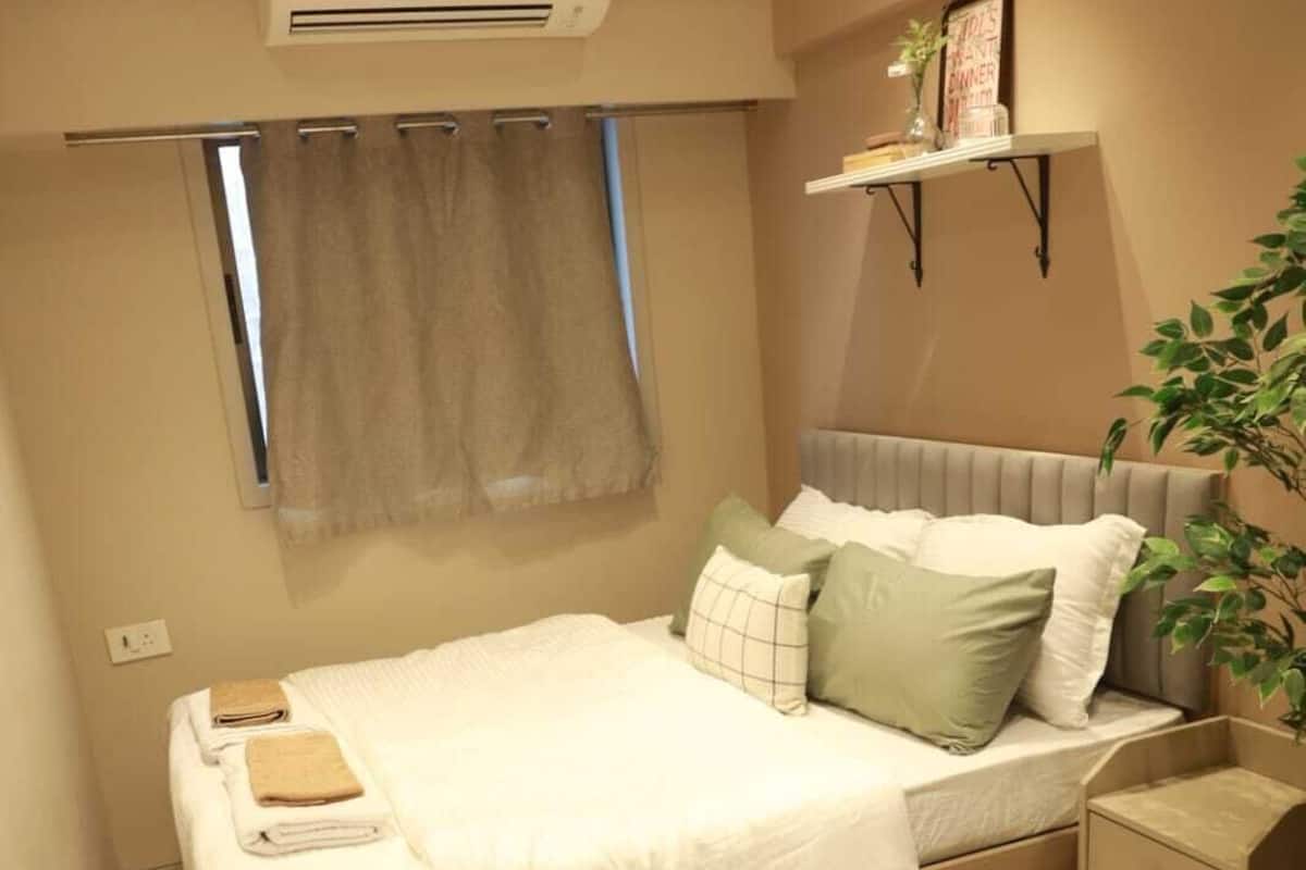 Un dormitorio ordenado con cama, mesita de noche y una pequeña estantería.
