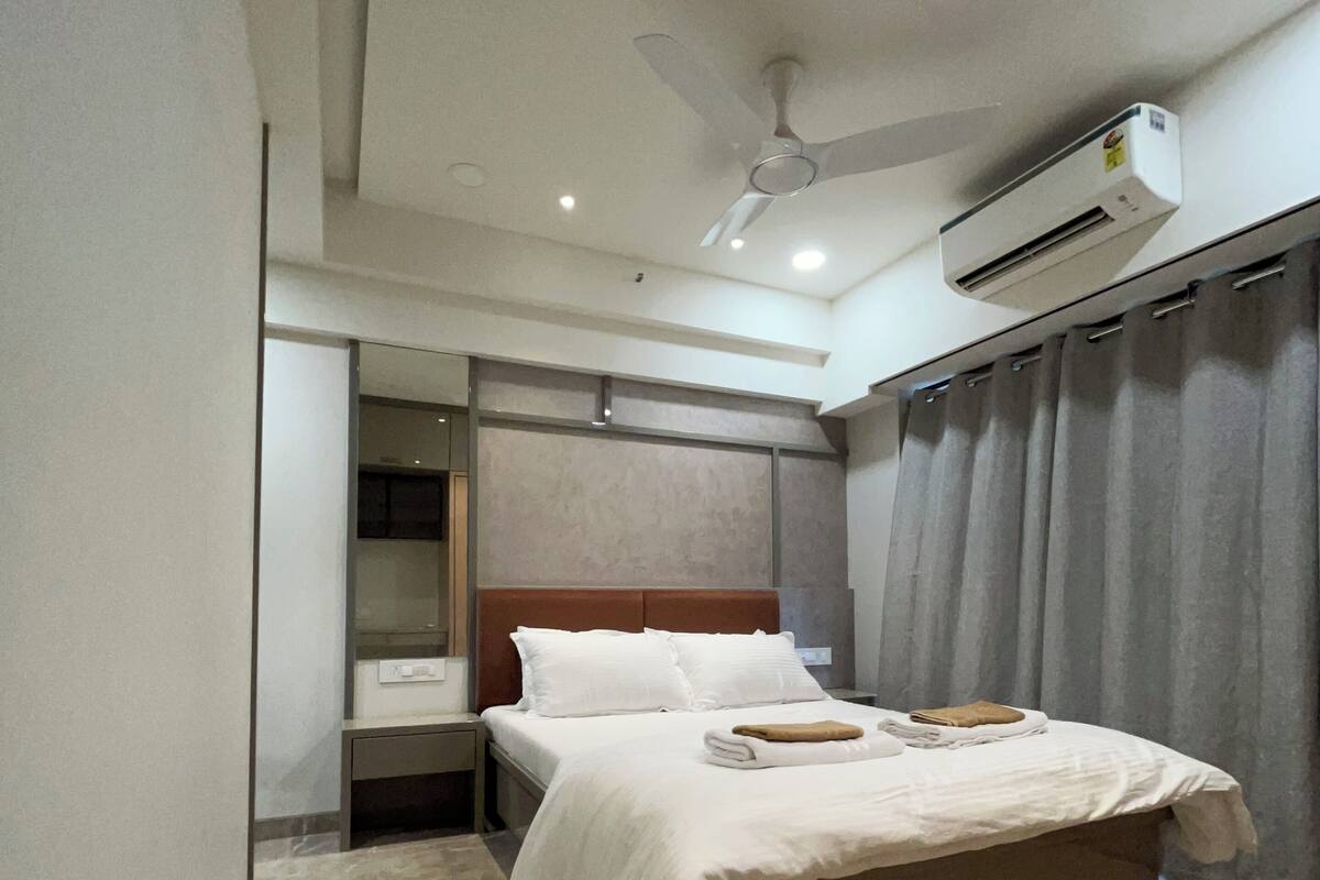 Habitación de hotel moderna con una cama grande, ventilador de techo, equipo de aire acondicionado y piso de mármol.