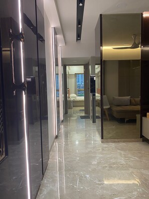 A modern hotel corridor with a glass door, a sofa, and a bed in the background. - Southside by Daily Stays (Mumbai)