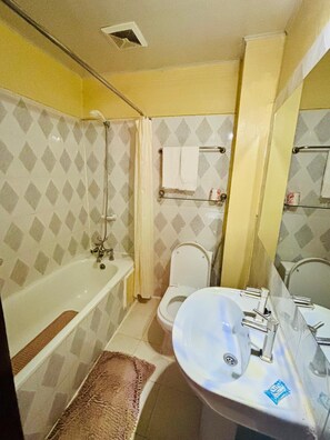 A bathroom with a bathtub, toilet, and sink. - FANG FANG SUITES (Kampala)