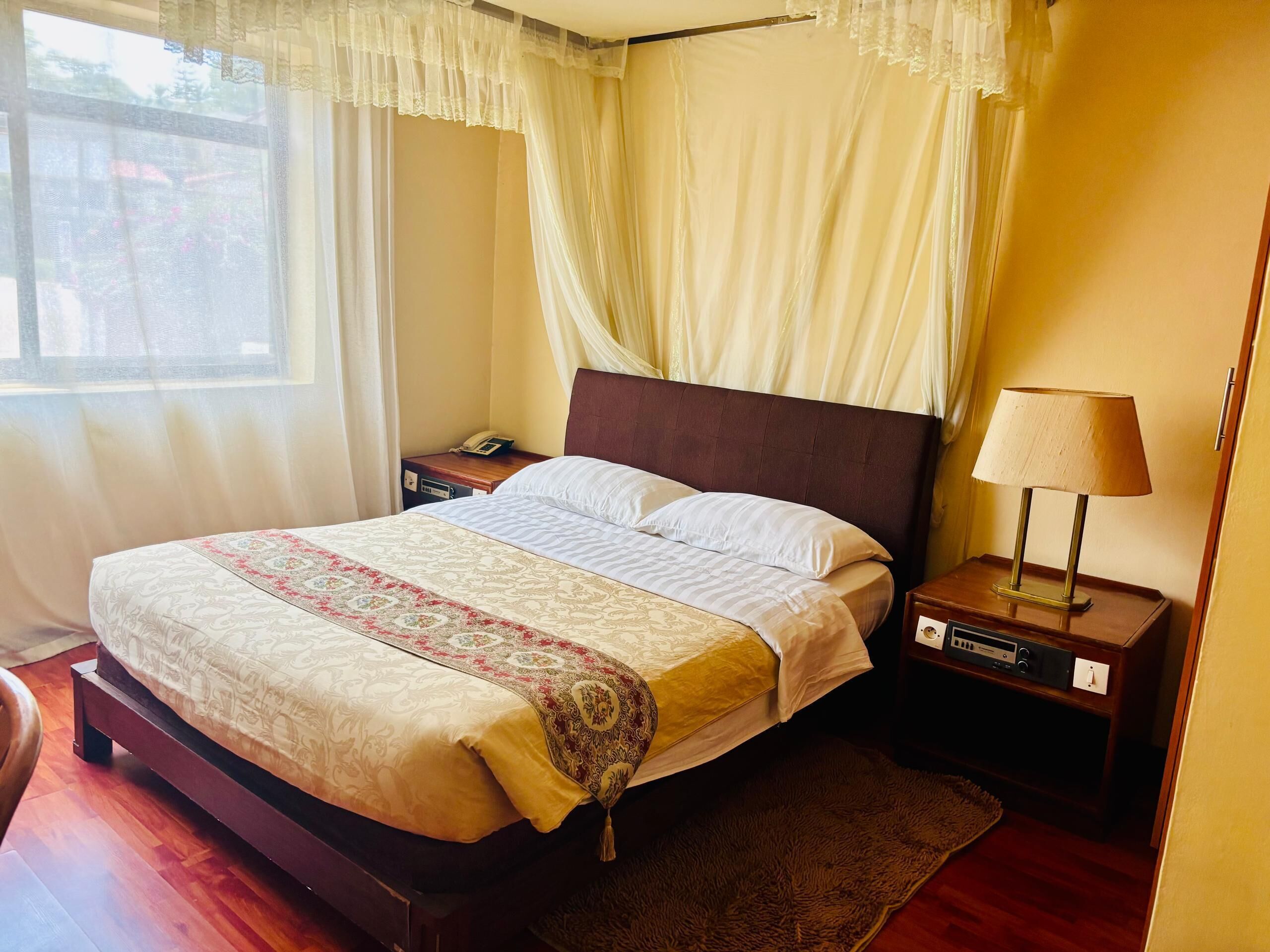 A neatly made bed with a patterned bedspread, a bedside table with a lamp, and a telephone.