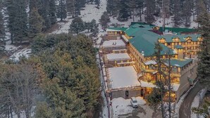 A large, multi-story building with a green roof, surrounded by snow-covered ground and trees. - Fortune Pahalgam  (Anantnag)