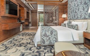 A modern bedroom with a large bed, a TV mounted on the wall, and a patterned rug. - Fortune Pahalgam  (Anantnag)