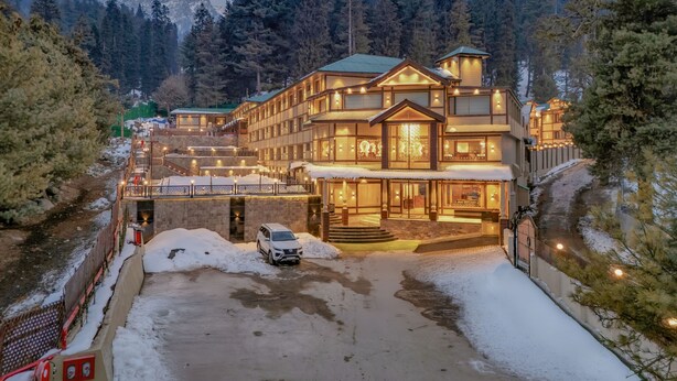 A multi-story hotel with a snow-covered driveway and a mountain backdrop. - Fortune Pahalgam  (Anantnag)
