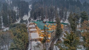 A lodge with multiple buildings, surrounded by snow-covered mountains and dense forests. - Fortune Pahalgam  (Anantnag)