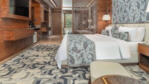 A modern bedroom with a large bed, a TV mounted on the wall, and a patterned rug. - Fortune Pahalgam  (Anantnag)