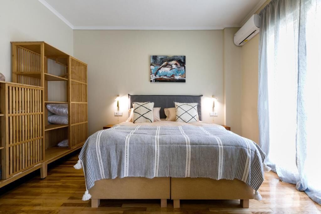 A bedroom with a bed, two bedside tables, a wooden wardrobe, and a painting on the wall.