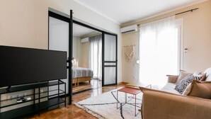 A modern living room with a flat-screen TV, a sofa, a coffee table, and a dining area. - Luxury A by OTOTO (Thessaloniki)