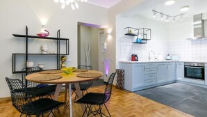 A modern kitchen with white cabinets, a black countertop, and a built-in oven. - Luxury A by OTOTO (Thessaloniki)