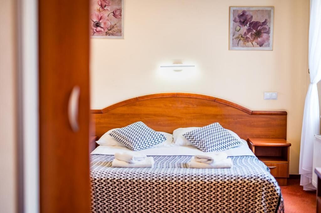 A neatly made bed with patterned bedding, a wooden headboard, and a bedside table with a lamp.