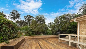 A wooden deck with a brick wall and a white railing on one side.