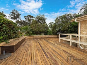 A wooden deck with a brick wall and a white railing on one side.