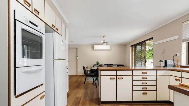 A kitchen with white cabinetry, a built-in oven, and a dining area with a table and chairs.