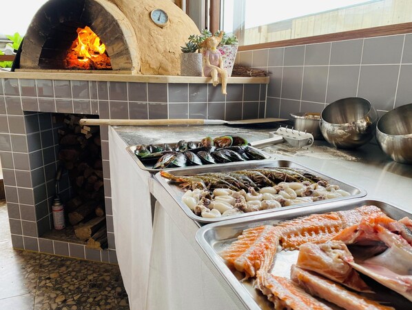 Una cocina con horno de leña, exhibición de mariscos y utensilios de cocina.