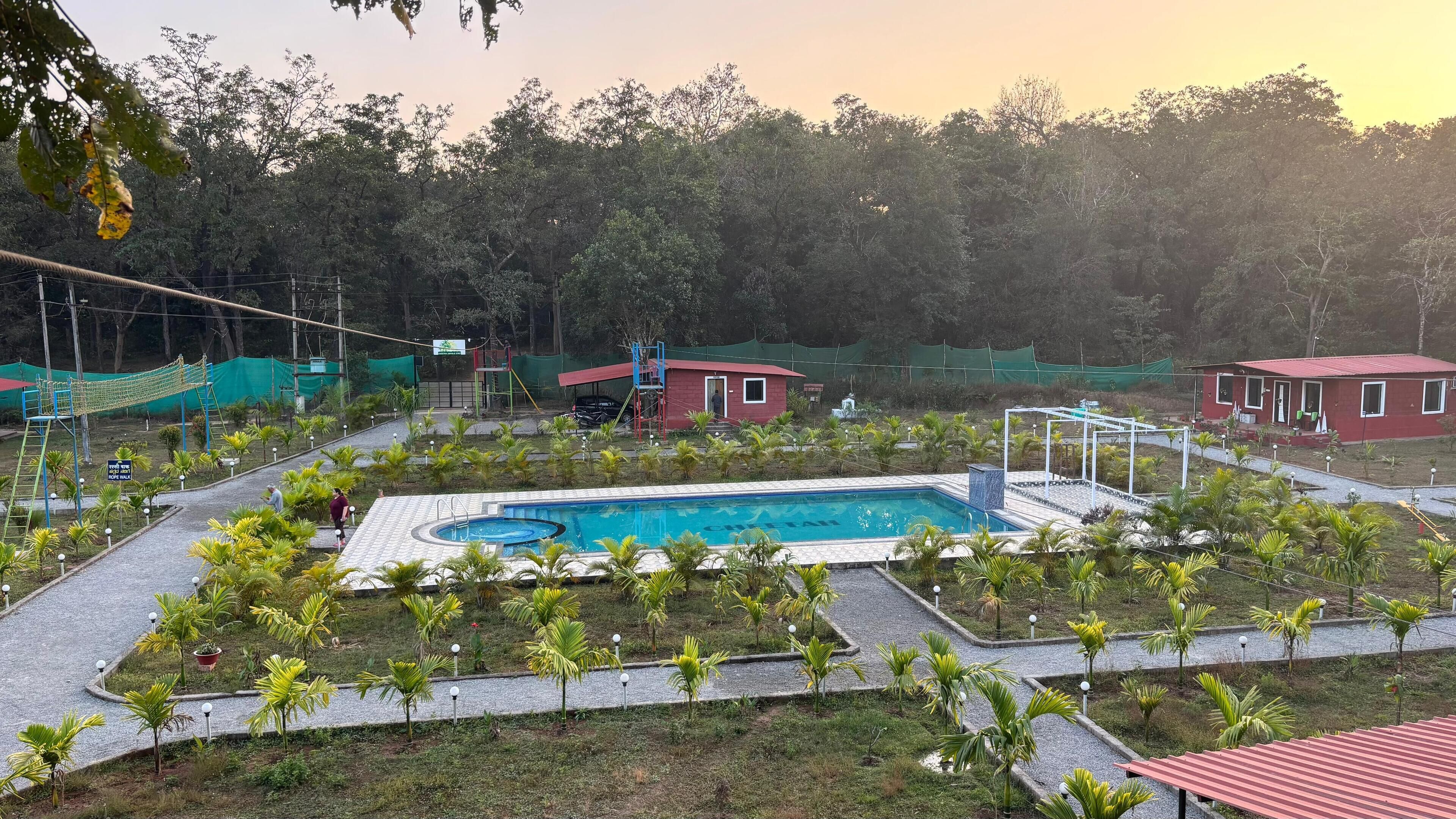 Ein Swimmingpool, umgeben von Palmen und einem Gebäude mit rotem Dach.