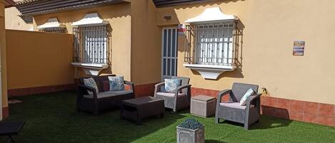 A pool area with a tiled edge, outdoor furniture, and a small garden.