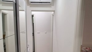 A narrow hallway with a wooden floor, white walls, and a bed with a floral bedspread on the right. - Apartman Sea Lake Magic 2 (Vinodol)