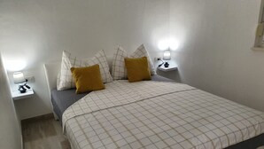 A neatly made bed with a checkered bedspread, two pillows, and a bedside lamp on each side. - Apartman Sea Lake Magic 2 (Vinodol)