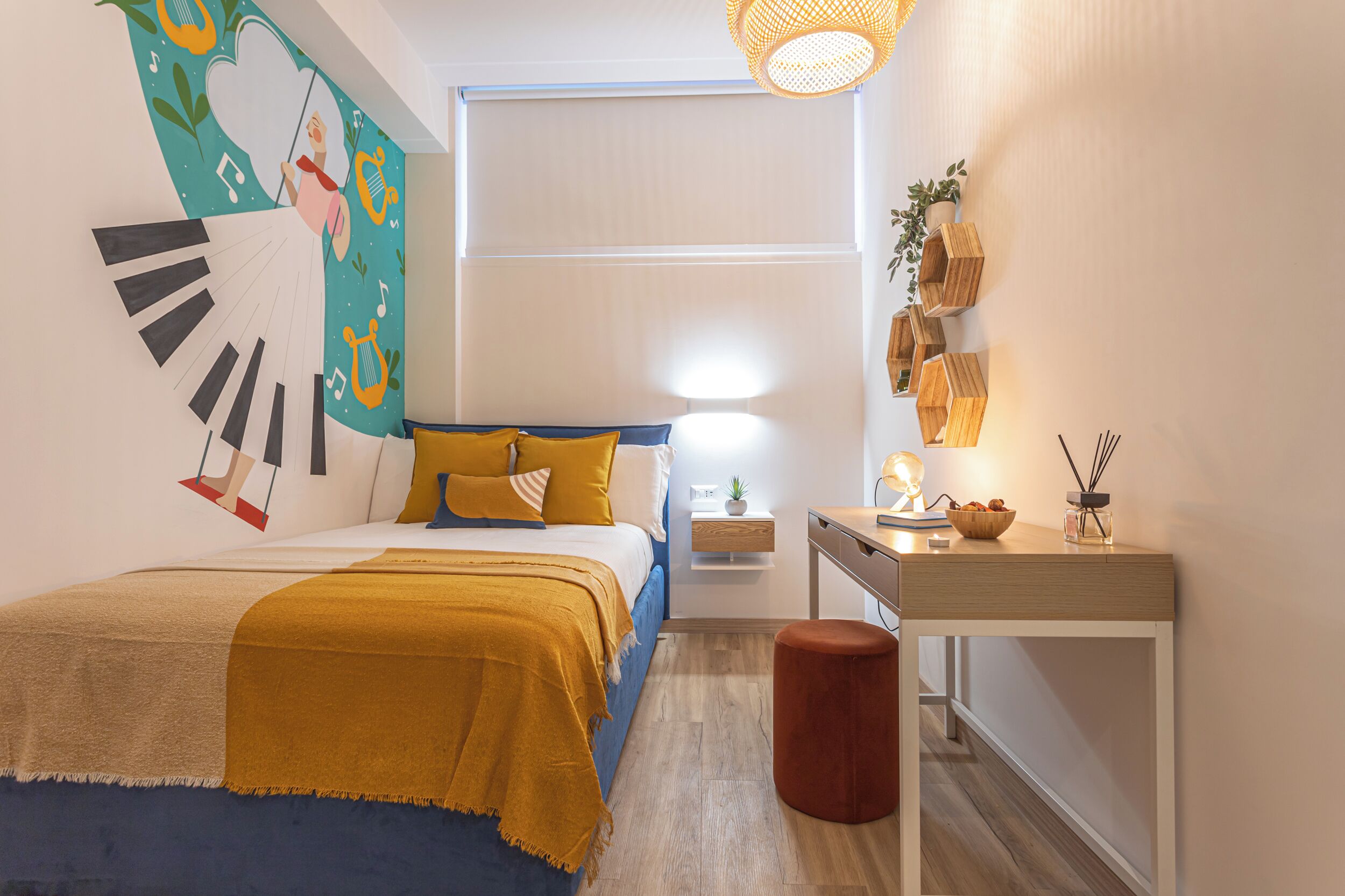 A bedroom with a bed, bedside table, and a desk with a chair.