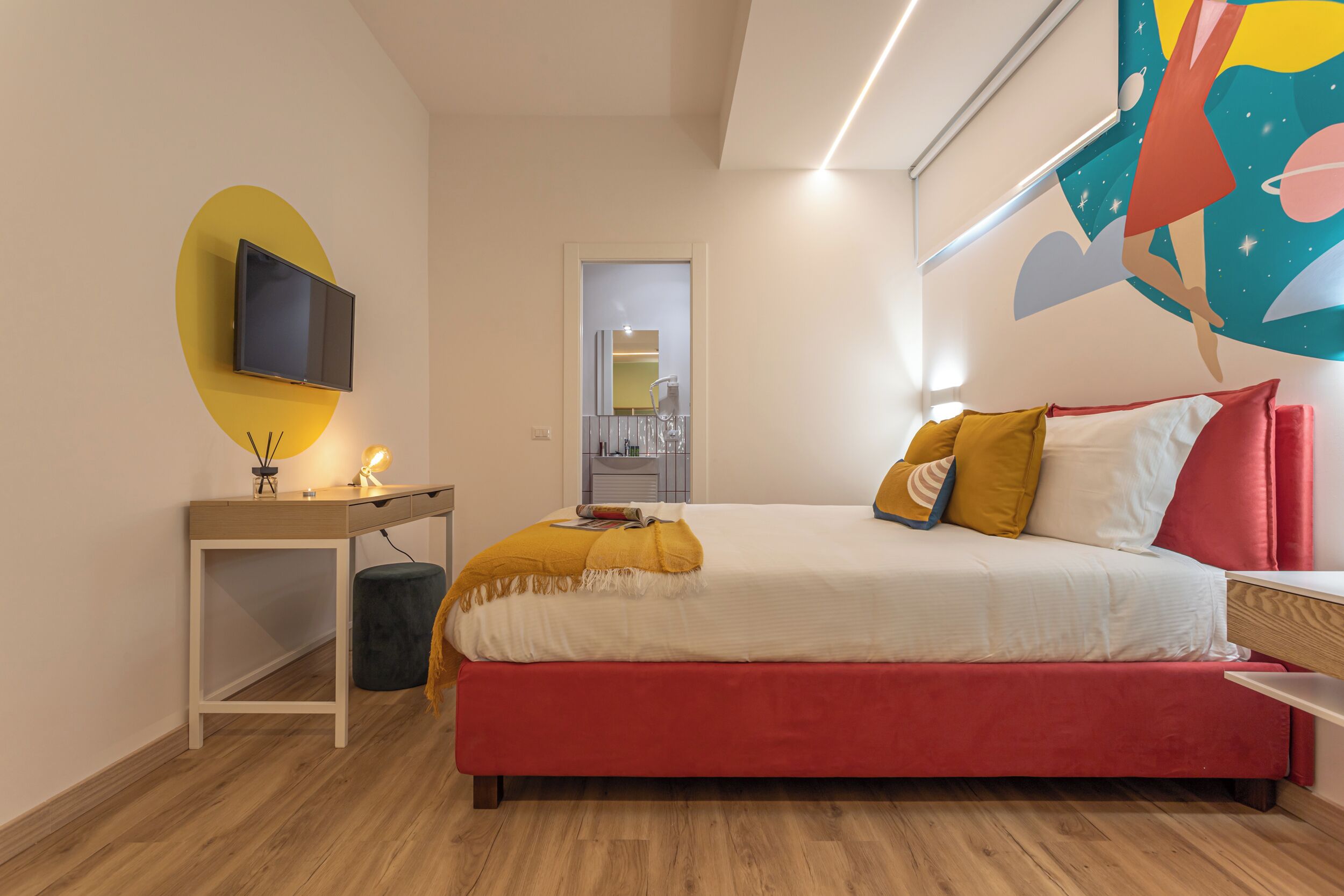 Ein modernes Schlafzimmer mit Bett, Nachttisch und einem an der Wand befestigten Fernseher.