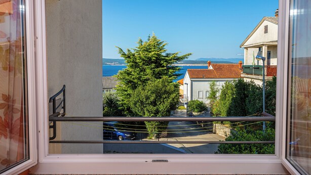 A balcony with a view of the sea, a tree, and buildings. - Apartman Mira (Crikvenica)