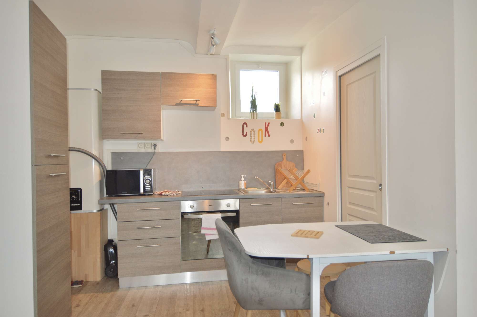 Une cuisine compacte équipée d’un four à micro-ondes, d’une cuisinière et d’une petite table à manger avec des chaises.