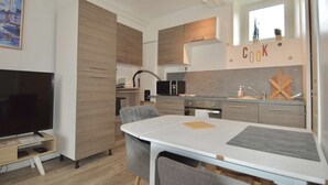 Una cocina moderna con comedor, televisor y un cartel que dice 'Cook'.