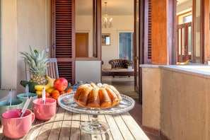 A dining table with a bundt cake, fruits, and pink mugs on a wooden table. - Sardinia RE - Dimora Della Contessa (Alghero)