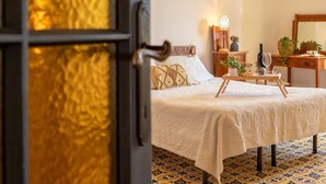 A bedroom with a bed, bedside table, lamp, and a mirror. - Sardinia RE - Dimora Della Contessa (Alghero)
